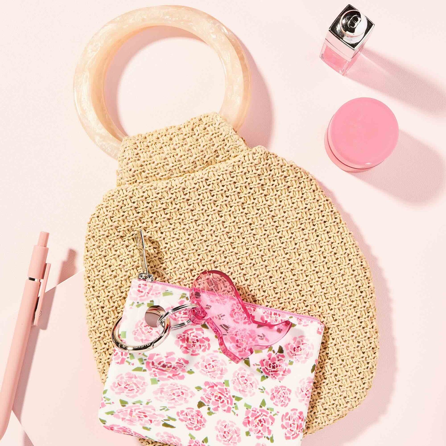 Beige sponge with pink floral pouch and lip balm on a pink background