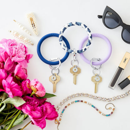 Silicone Big O Key Ring in Midnight Navy, Navy Leopard and In the Cabana laying flat with flowers, hair accessories, sunglasses and jewelry 