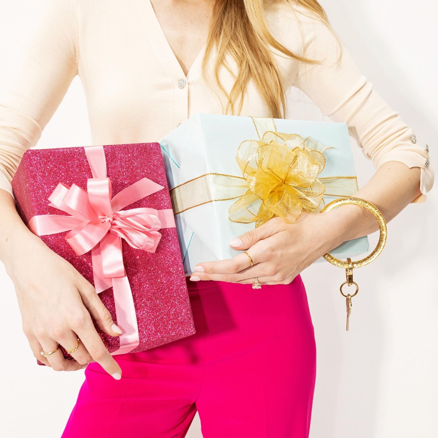 Woman carrying gift boxes while wearing the Oventure Original Resin Big O® Key Ring in Champagne, a gold glitter bracelet keychain and hands-free key holder for women, gifting, holidays, and special occasions.