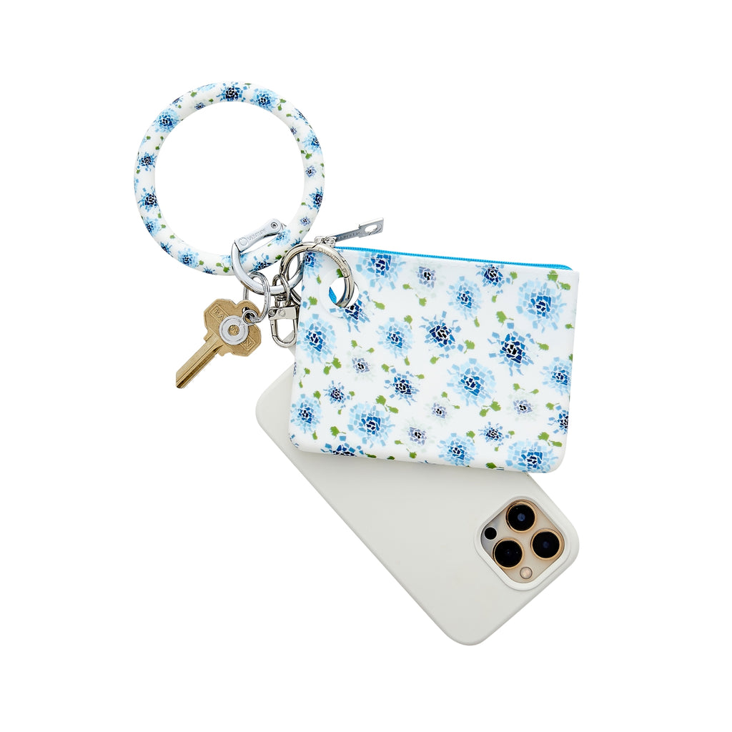 A big O key Ring and mini silicone pouch attached together. There is also a phone connector to attache the cell phone. The print has a blue hydrangea print.