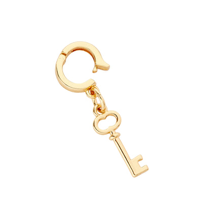 A gold-colored key-shaped charm with a polished finish and a secure huggie closure, designed for clipping onto accessories like bracelets and wristlets.