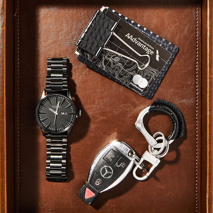 Watch, cardholder, and keychain set on a brown leather surface