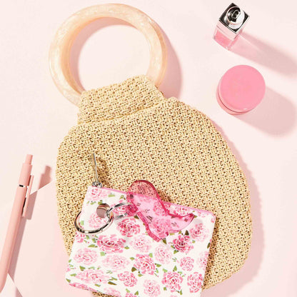 Beige sponge with pink floral pouch and lip balm on a pink background