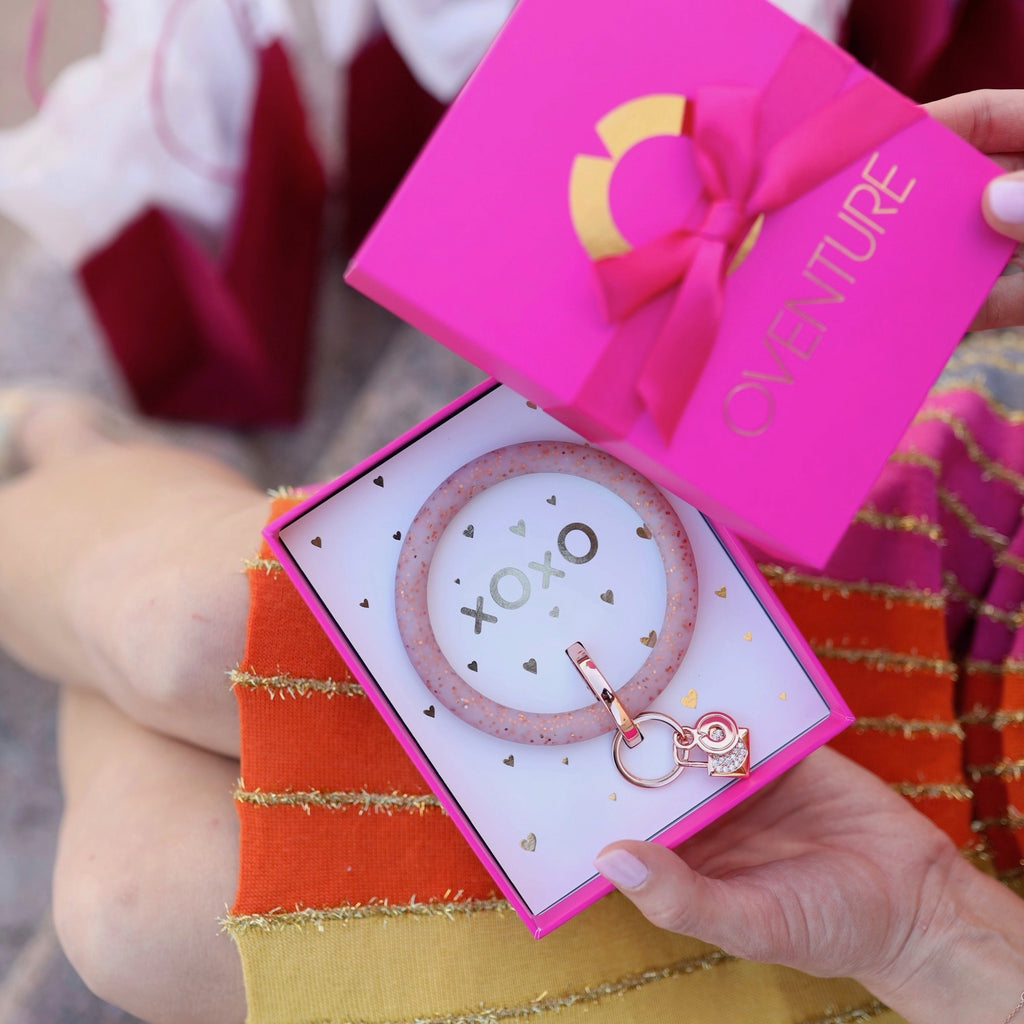 Silicone Rose Gold Confetti Big O Key Ring with Rose Gold Lock Charm placed inside a hot pink Oventure box that says xOxO in gold