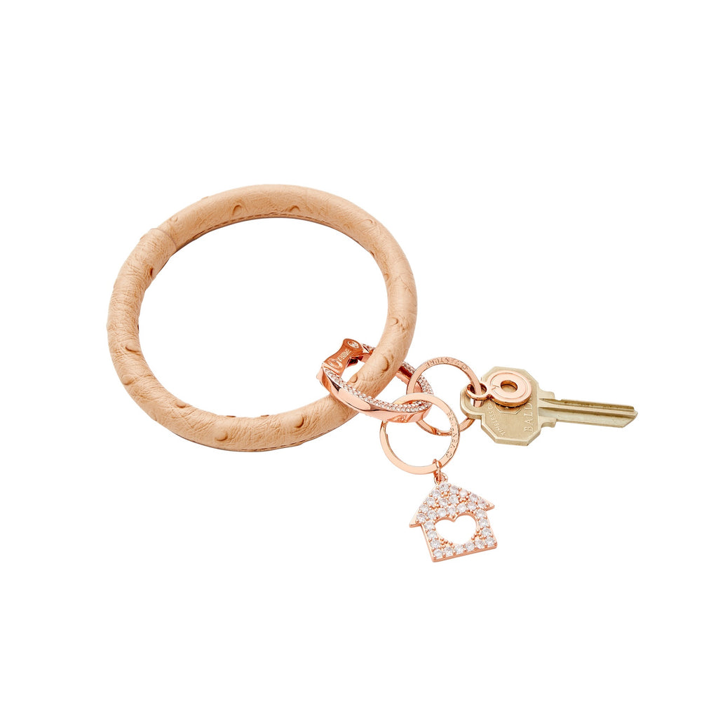 Mocha ostrich big o keyring with a home is where the heart is charm attached in rose gold. This charm has a cutout center heart and is bejeweled