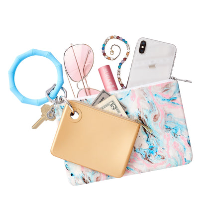 Layered handsfree set which includes a Big O Key Ring in Sweet Carolina blue and is bamboo shaped.  A large silicone pouch in marble pastel has an iPhone lip gloss and sunglasses inside.  