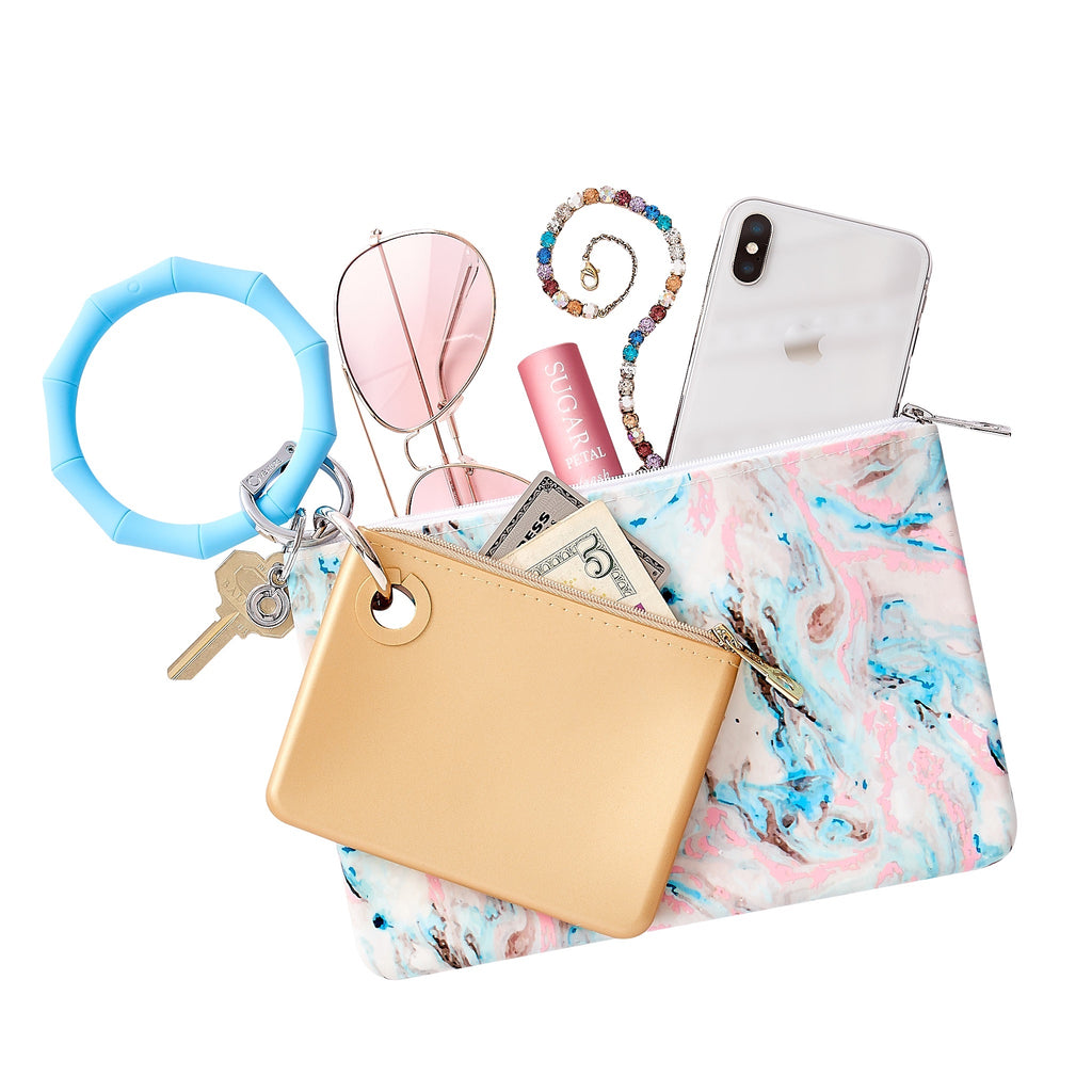Layered handsfree set which includes a Big O Key Ring in Sweet Carolina blue and is bamboo shaped.  A large silicone pouch in marble pastel has an iPhone lip gloss and sunglasses inside.  