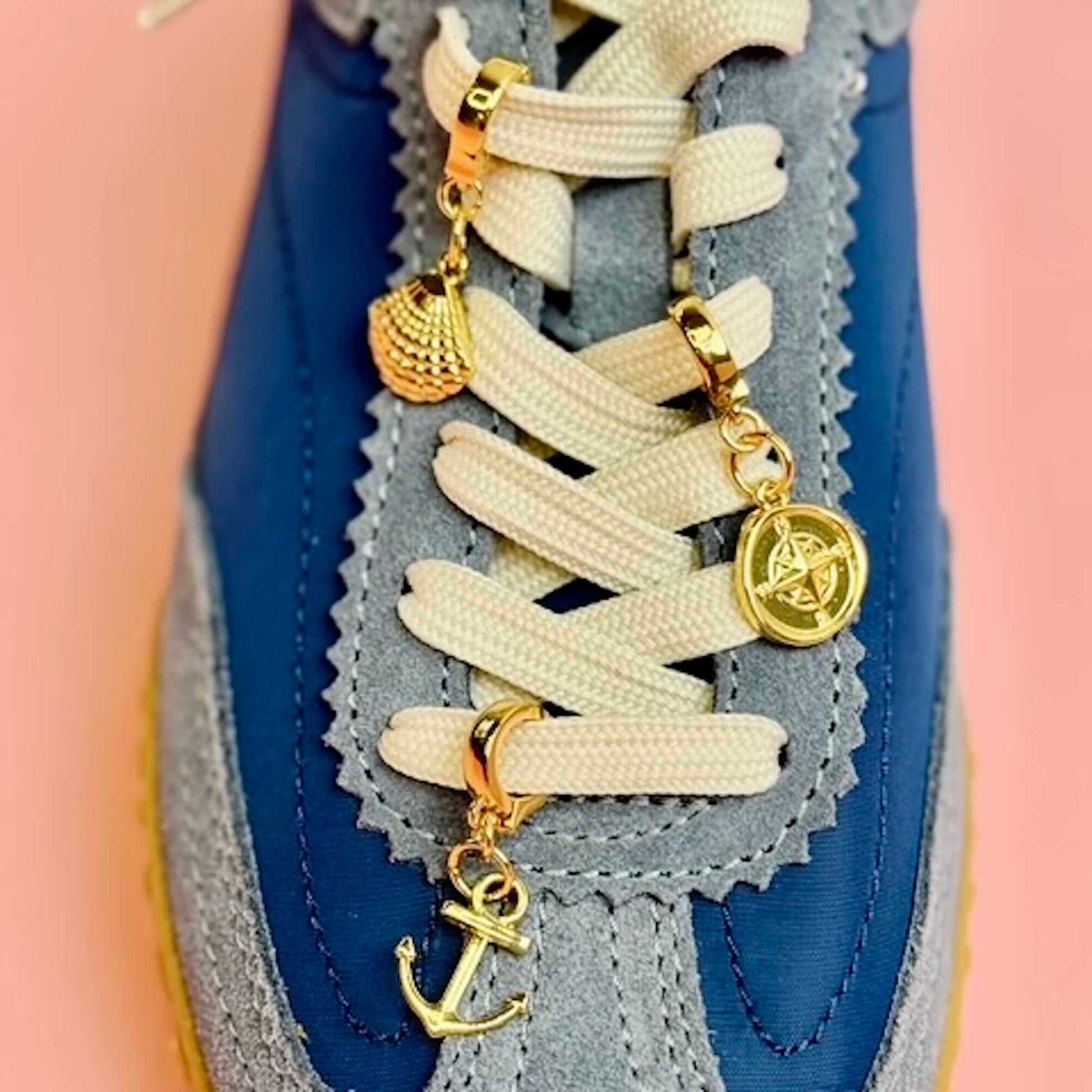 Gold charms in an anchor, compass and shell on shoe laces