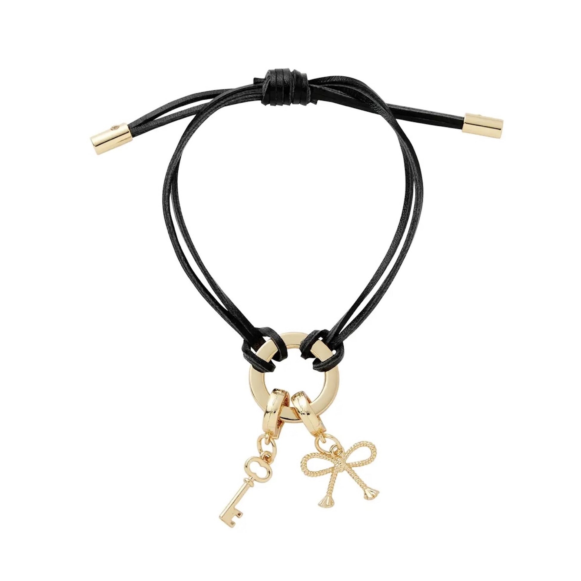 Black cord bracelet with gold key and bow charm on a white background