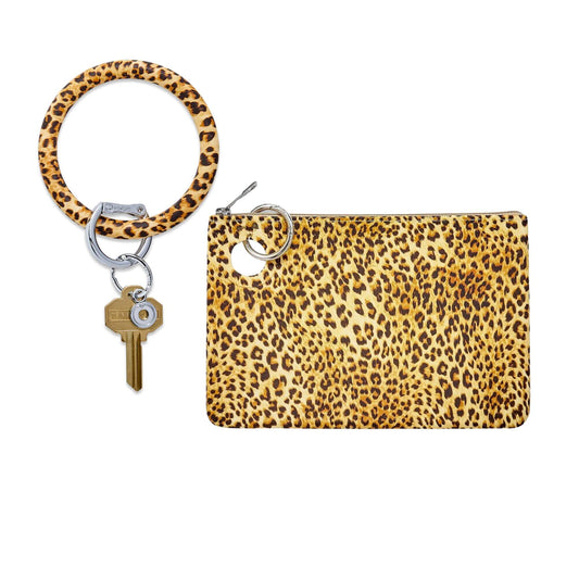 Leopard-print silicone Big O® Key Ring with silver clasp and gold house key, paired with a matching large silicone pouch wristlet in bold cheetah pattern, shown on a white background.
