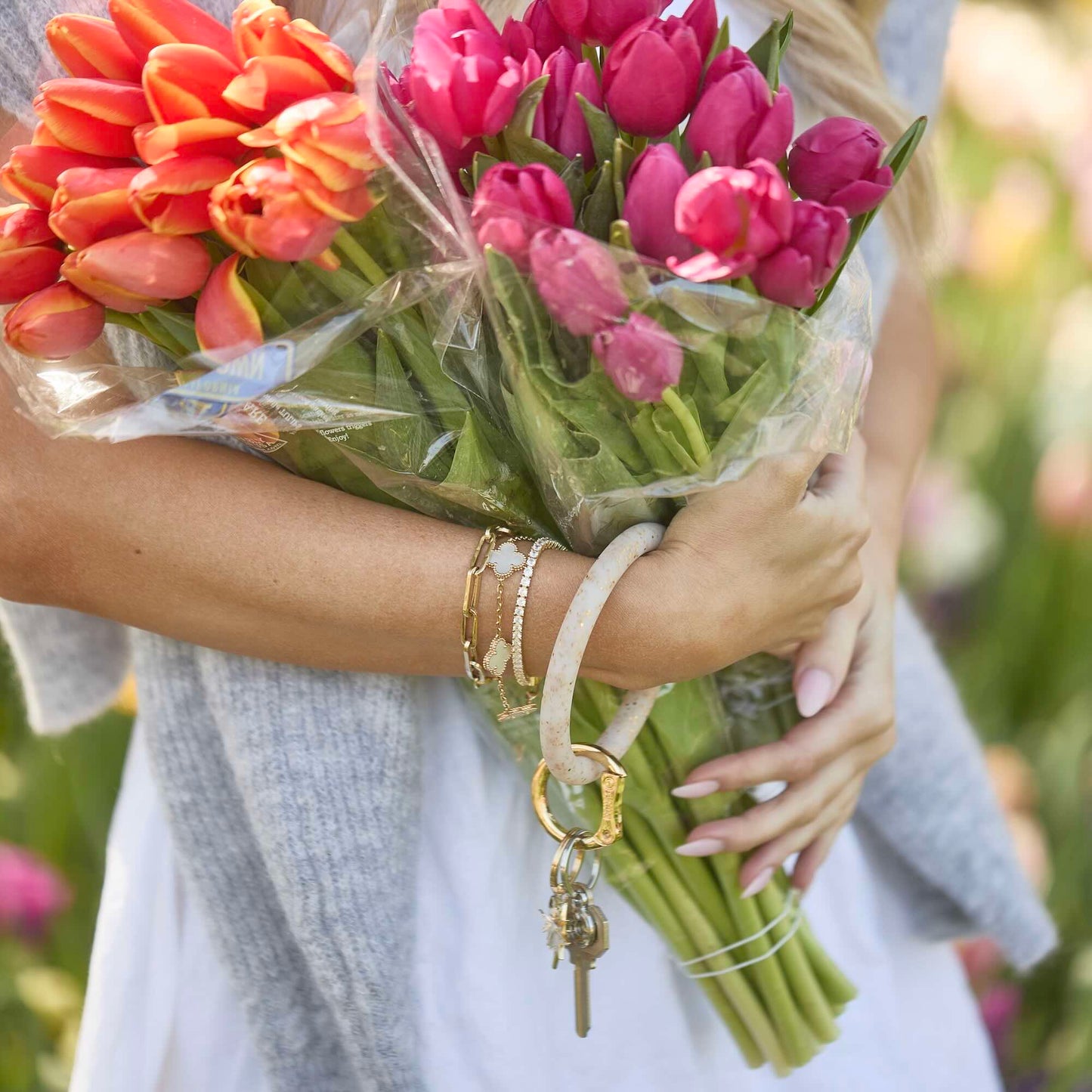 Woman wearing Gold Confetti Silicone Big O® Key Ring on wrist, holding keys and flowers for hands-free carry