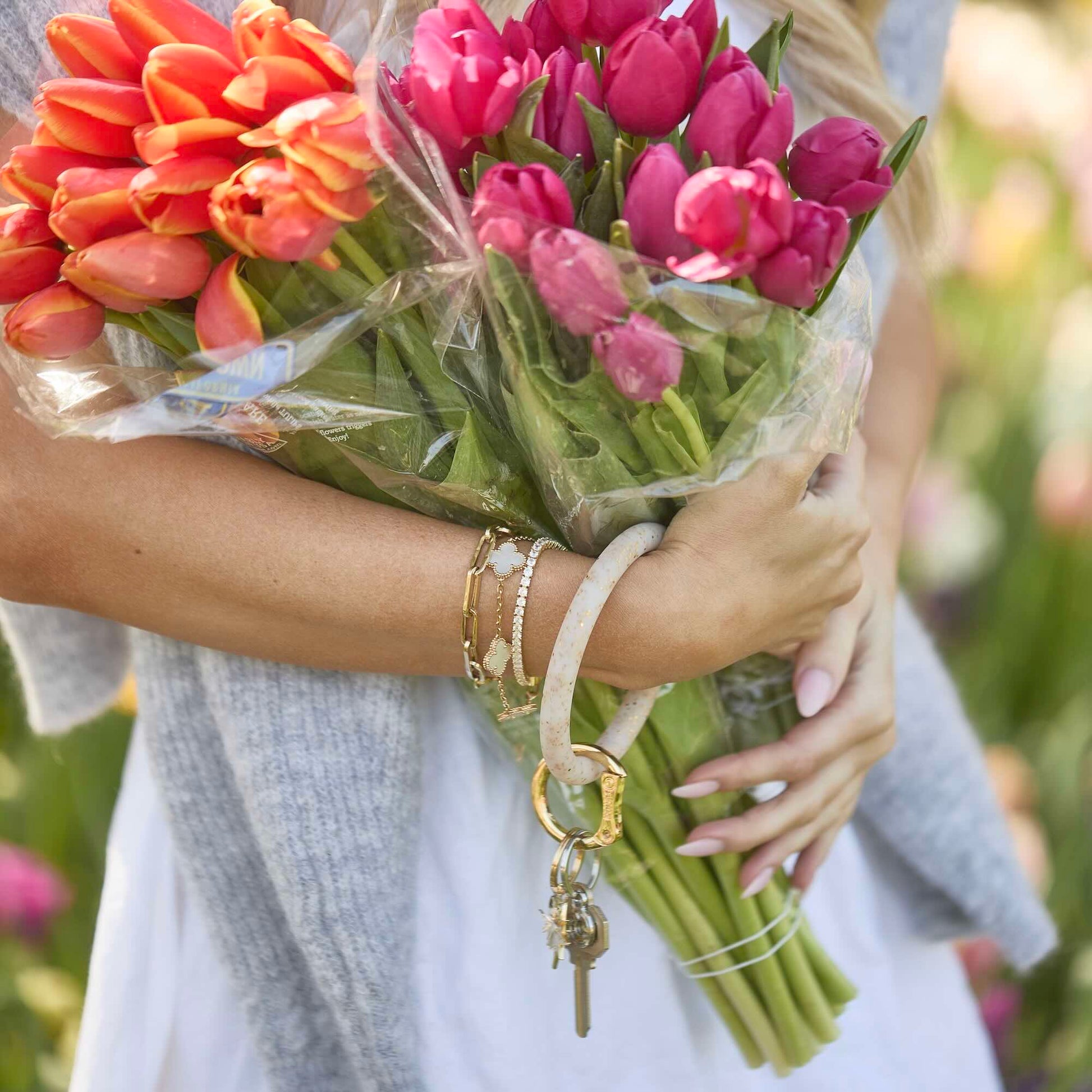 Woman wearing Gold Confetti Silicone Big O® Key Ring on wrist, holding keys and flowers for hands-free carry
