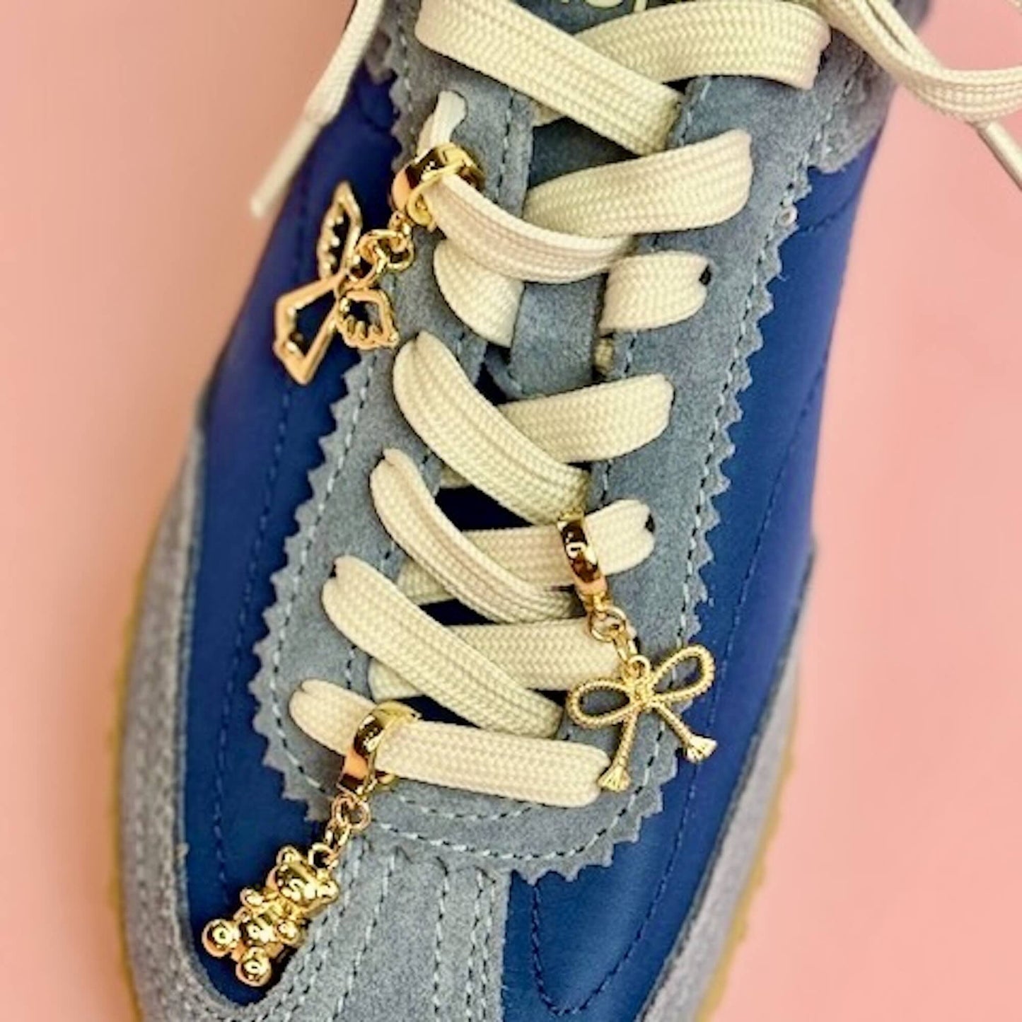 Gold charms in an angel, bow and teddy bear on laces for an updated shoe charm look 