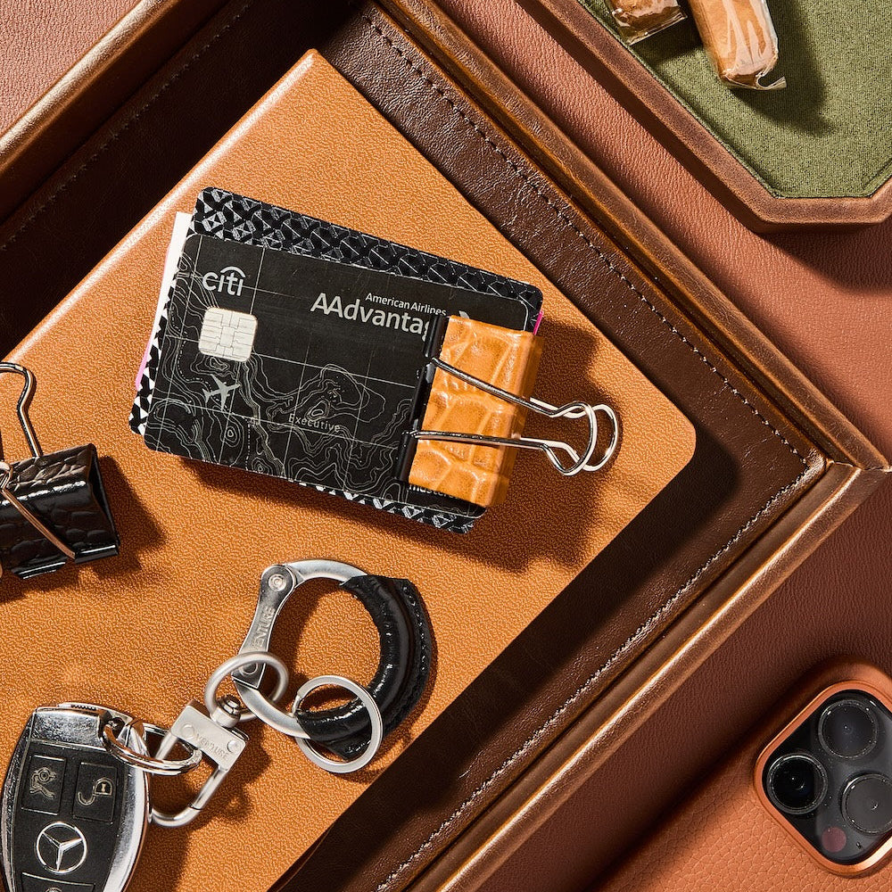 Cardholder with 'Advanta' branding on a brown leather surface with car keys and phone.