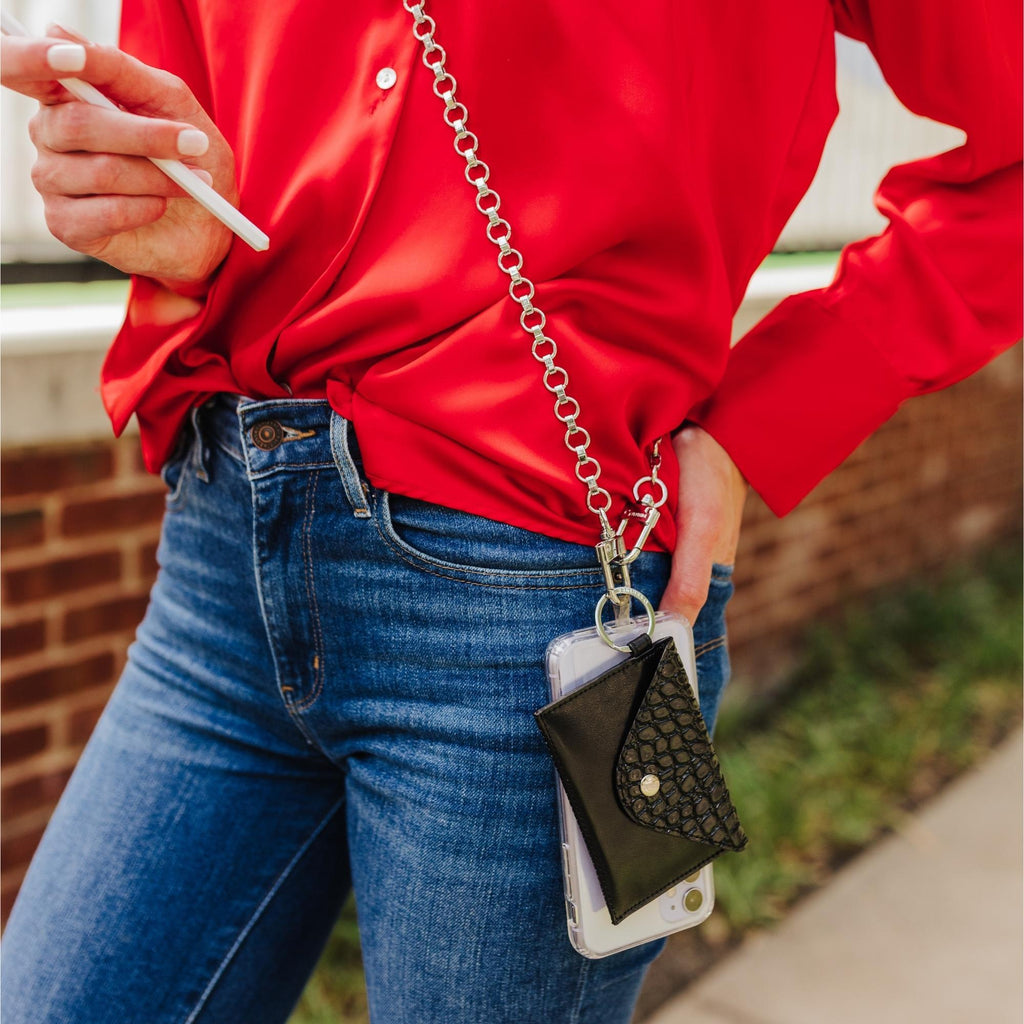A crossbody chain with a black small wallet attached and the phone attached